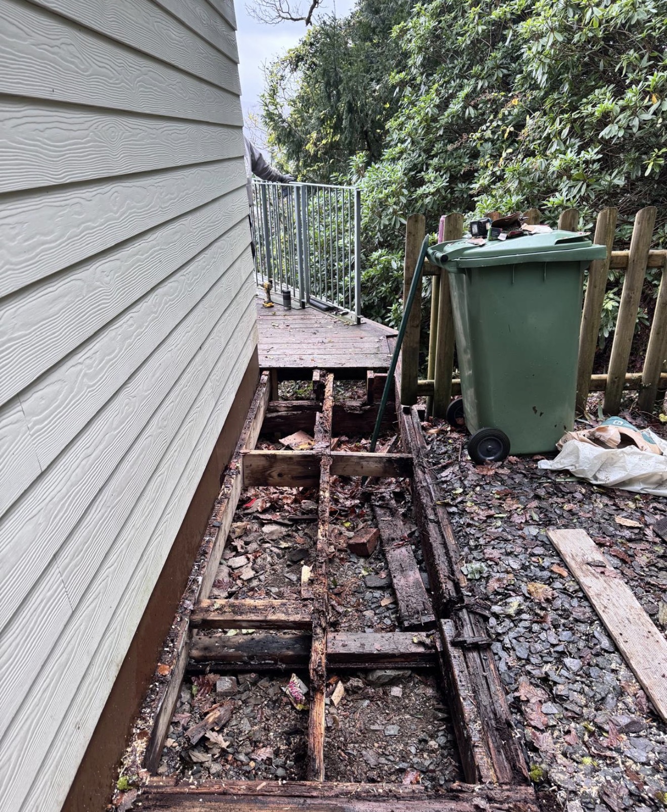 Rotten timber decking before replacement beside a property